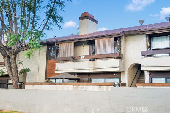 Front view of a two-story residential building with balconies and a chimney.
