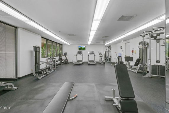 Interior view of a gym with various exercise equipment including treadmills and weight machines.