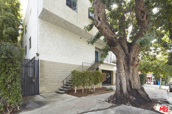 Front view of a multi-story building with exterior stairs and a gated entrance.