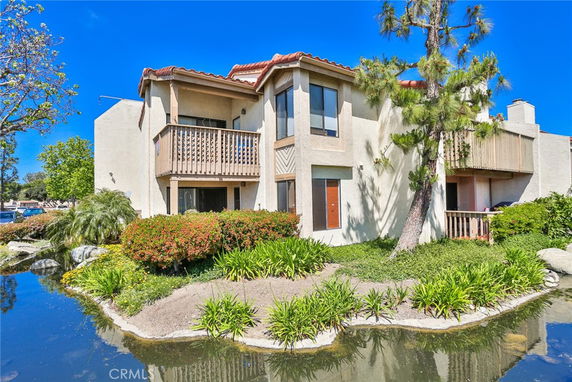 Front view of a house with a balcony and a pond.