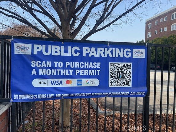 Public parking area with a sign displaying payment options and a QR code for purchasing a monthly permit.