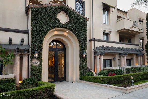 Front view of a multi-story building with arched entrance and balcony.