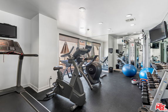 Indoor gym area with exercise equipment and weights.