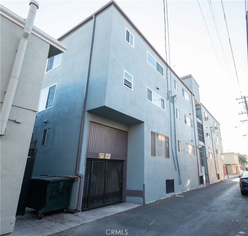 Side view of a three-story building with multiple windows and a gated entrance.
