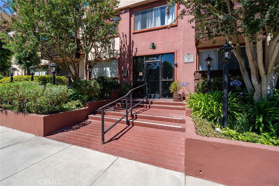 Front view of a building entrance with steps and landscaping.