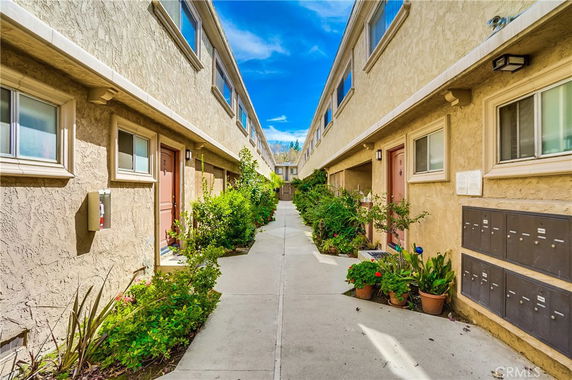 Front view of a two-story apartment complex with outdoor corridor and mailboxes.