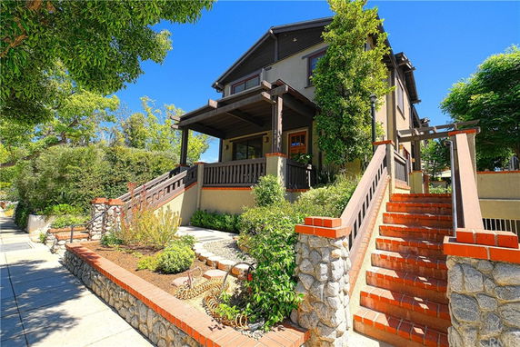 Front view of a two-story house with a porch and brick steps.