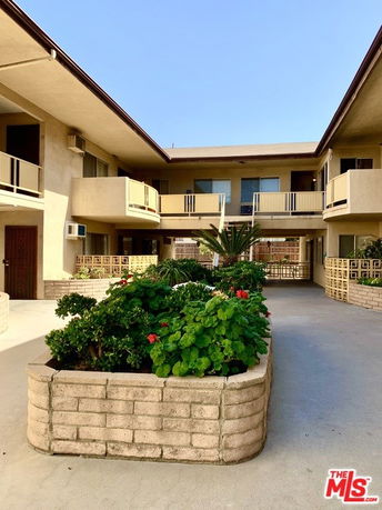 View of multi-story apartment complex with balconies and central courtyard.