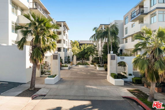 Front view of a multi-story apartment building with palm trees.
