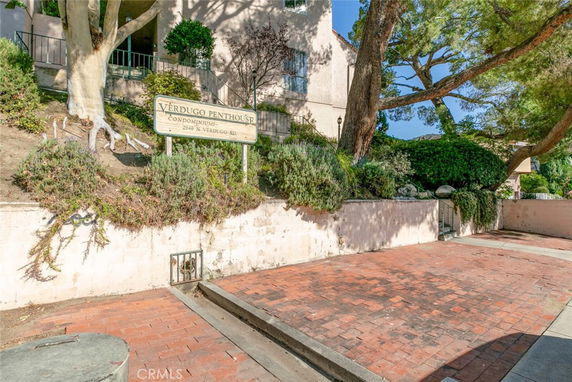 Front view of a condominium building with signage and brick driveway.