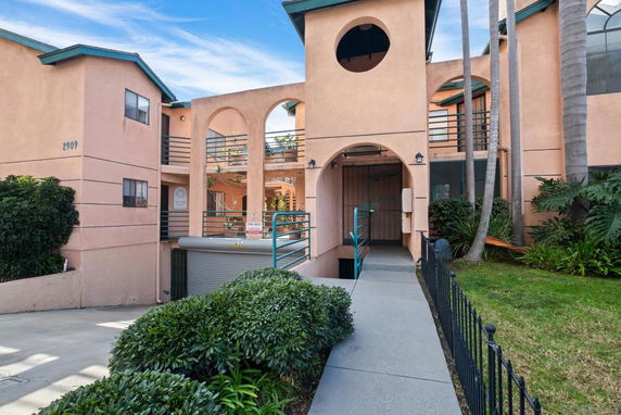 Front view of a multi-story building with arched openings and a ramp entrance.