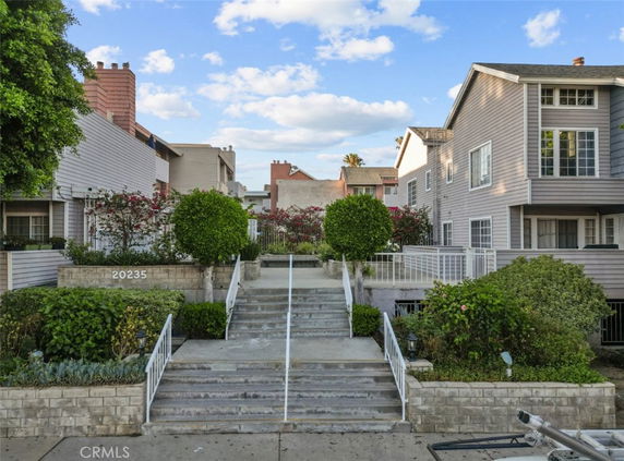 Front view of a multi-story residential building with landscaped entrance and steps.