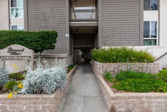 Front view of a condominium building entrance with landscaped pathway.