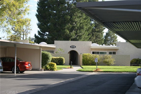 Outdoor parking area with covered parking and visible house entrance.