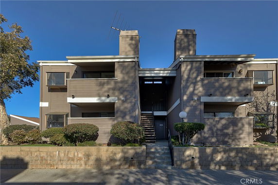 Front view of a multi-story apartment building with two chimneys and a central stairway.