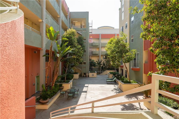 View of a multi-level apartment building with open courtyard and potted plants.