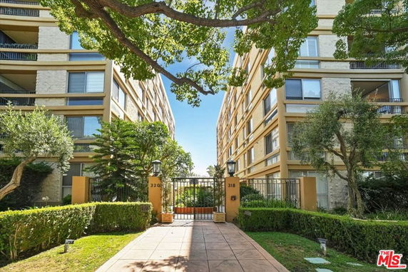 Front view of two multi-story residential buildings with a central walkway and a gated entrance.
