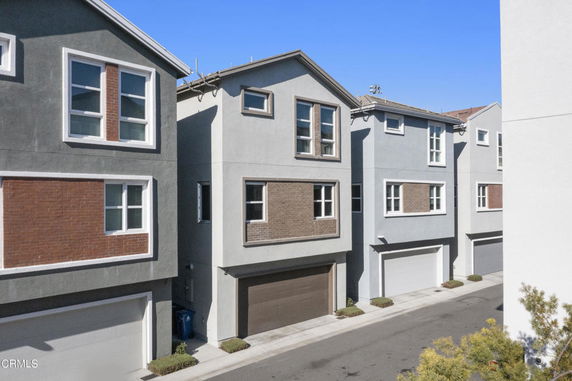 Front view of a row of multi-story modern houses with garages.