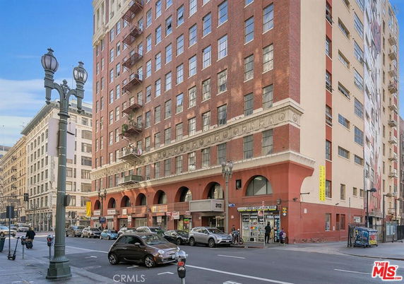 Front view of a multi-story brick and concrete building with street level shops and large windows.