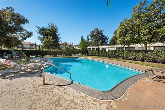 Outdoor swimming pool area with lounge chairs and surrounding greenery.