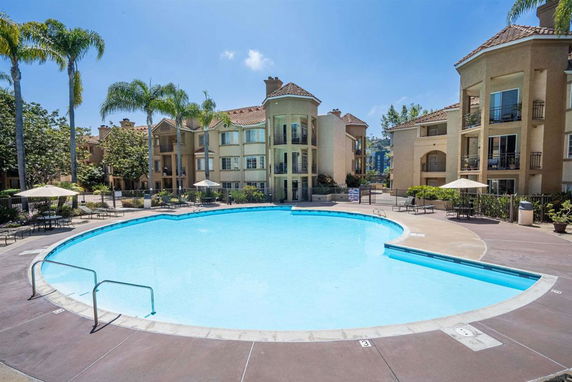 Outdoor swimming pool area with surrounding multi-story apartment buildings.
