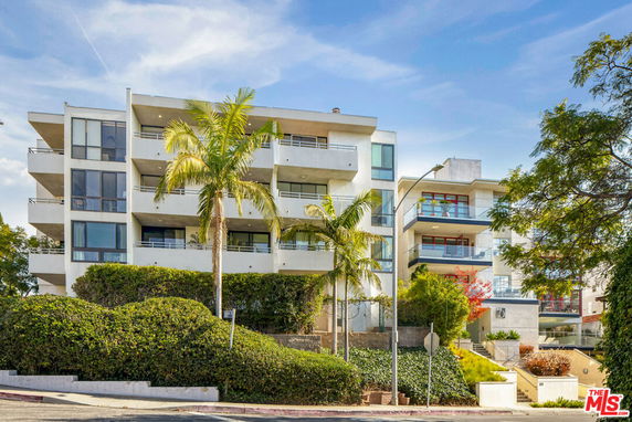 Front view of a multi-story residential building with balconies and large windows.