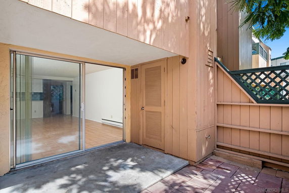 Exterior view featuring a sliding glass door entrance with wooden siding.