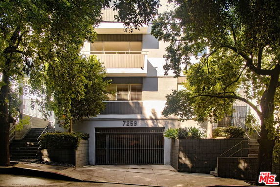 Front view of a multi-story building with balconies and a gated entrance.
