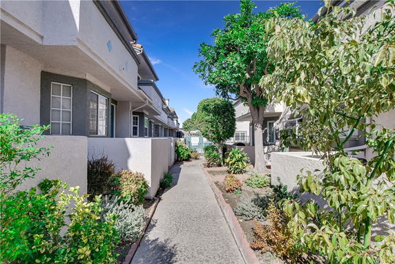 View of multiple connected residential buildings with windows and small gardens along a pathway.