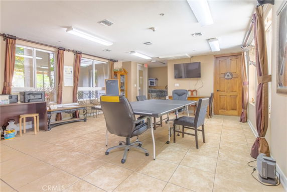Recreation area with meeting table and seating, featuring a wall-mounted TV.