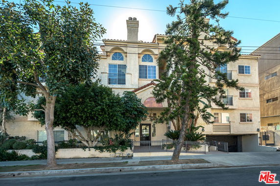 Front view of a multi-story residential building with arched windows and balcony railings.