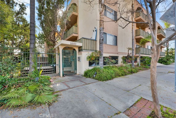 Front view of a multi-story residential building with balconies and a gated entrance.
