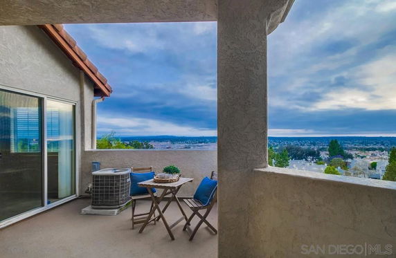 Outdoor area with chairs and table, overlooking a wide cityscape view.