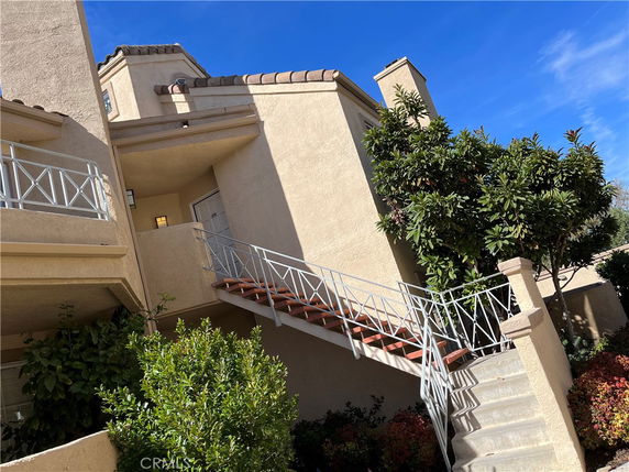 Front view of a multi-level house with a staircase leading to the entrance.