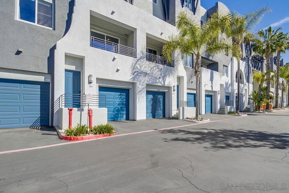 Front view of a multi-story building with blue garage doors and balconies.
