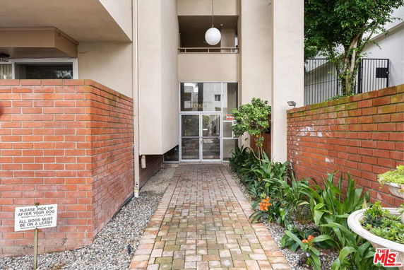 Front view of a building entrance with brick pathway and plants.