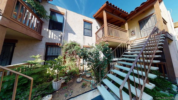 Front view of a two-story building with outdoor stairs and wooden railings.
