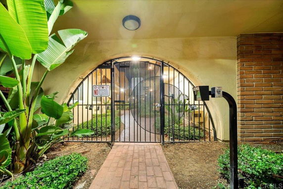 Front view of a building entrance with a gated archway and brick pathway.