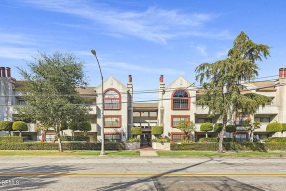 Front view of a multi-story residential building with symmetrical design and red trim accents.