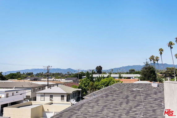 Panoramic view showing rooftops with mountains and trees in the background