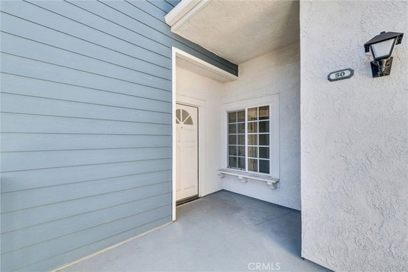 Front entrance of a house with a white door and window, next to a blue siding wall.