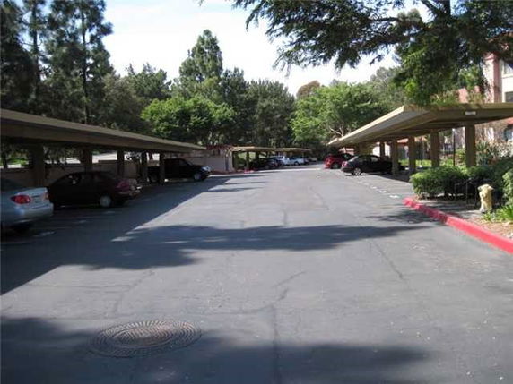 Outdoor parking area with covered parking spaces and surrounding trees.