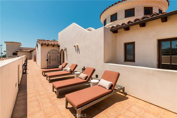Rooftop area with lounge chairs and Mediterranean-style architecture.