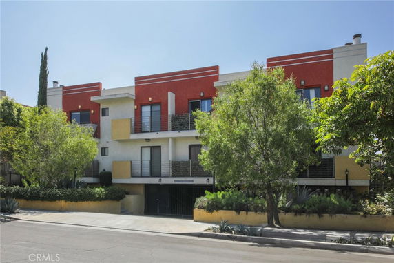 Front view of a modern multi-story building with balconies and large windows.