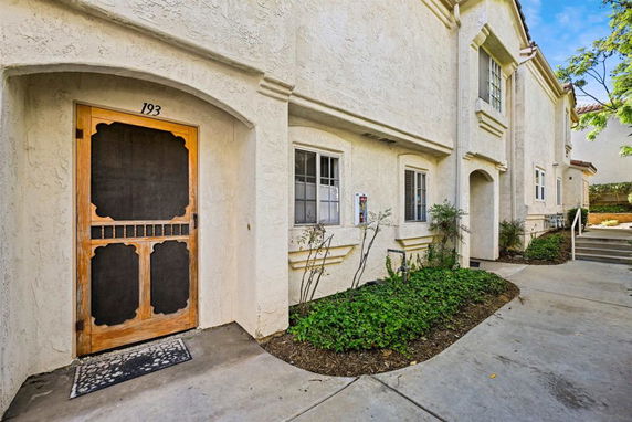 Front view of a two-story residential building with an arched entryway and windows.