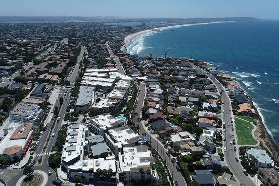 Panoramic view of a coastal city with numerous houses and buildings along the shoreline.