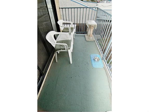 Balcony with plastic chairs and railing overlooking surrounding area.