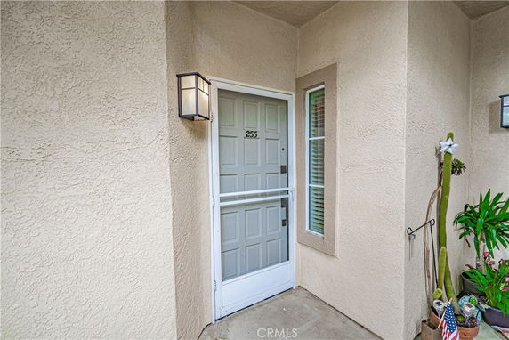 Front view of a beige-colored house entrance with a white door and a small window.
