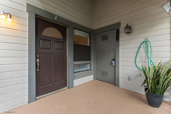 Entrance view of a residential unit with a brown door and an adjacent utility area.