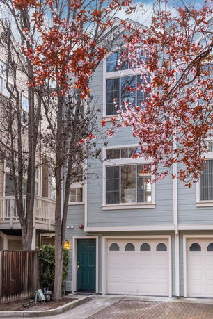 Front view of a multi-story townhouse with a garage and a green door.